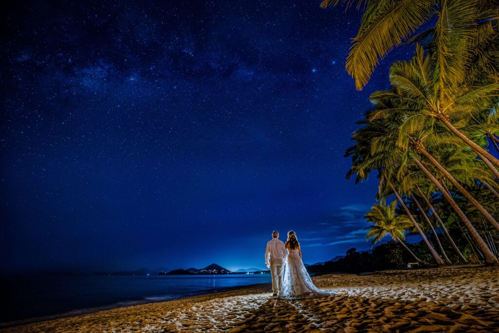 newlywed couple walking down the beach on a starry night