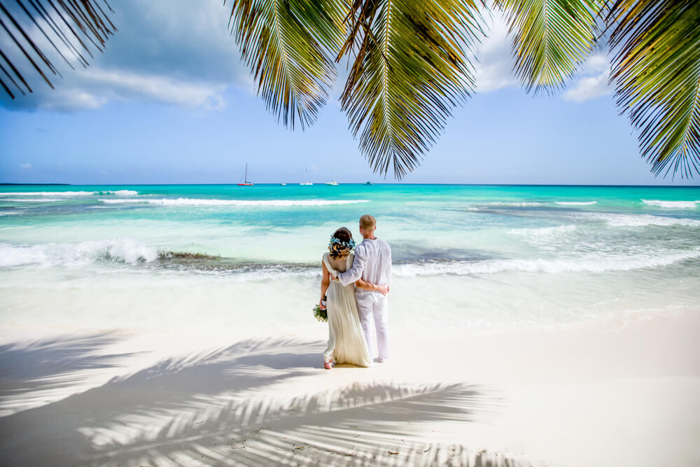 newlyweds hugging at white sandy beach