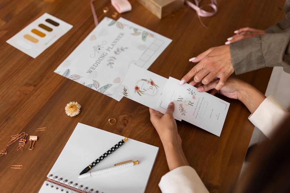 2 female wedding planners comparing invitation designs, wedding planning concept