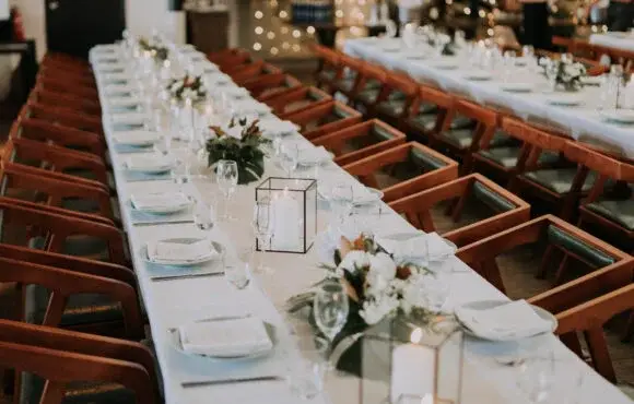 Empty long table with classy wooden chairs and white placemats