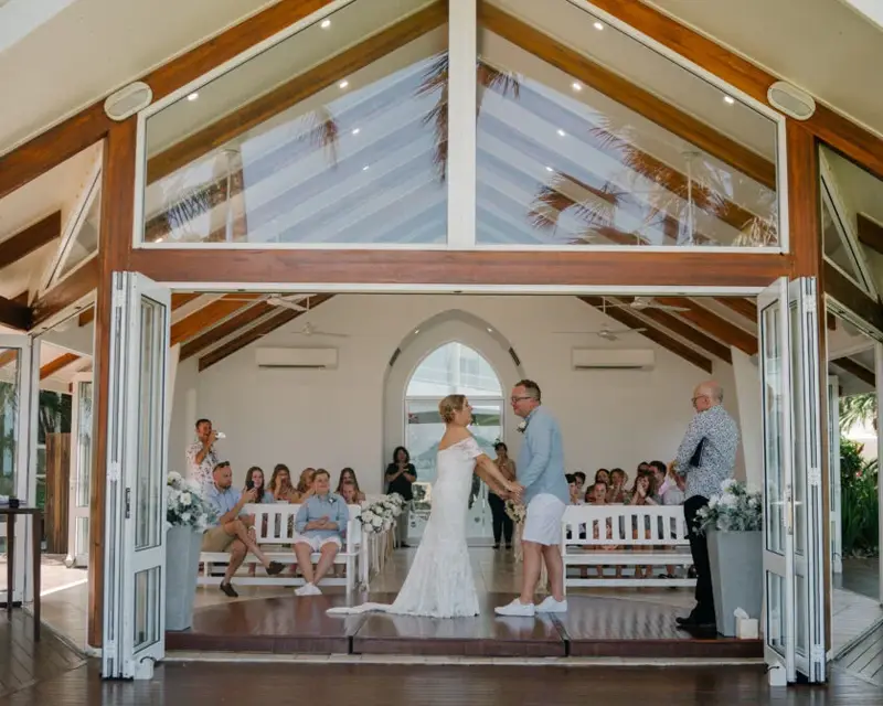 Bride and groom holding hands in front of the Alamanda chapel