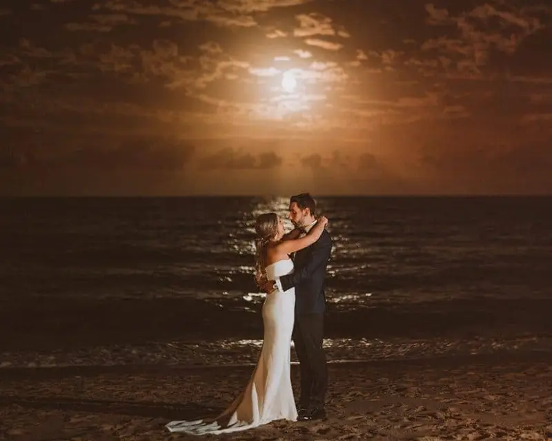 Husband and wife dancing as night in front of the ocean