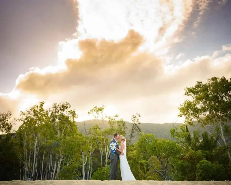 Newlyweds kissing with a beautiful backdrop at Palm Cove wedding venues