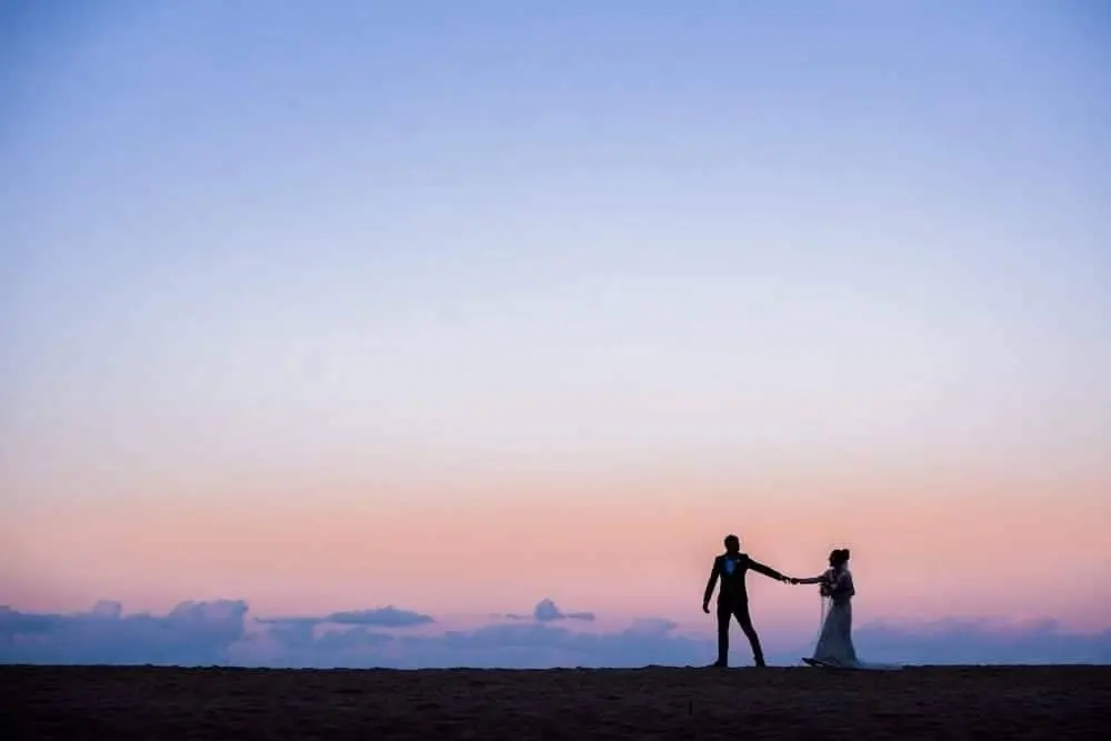 Silhouette of a bride and groom as the sun sets