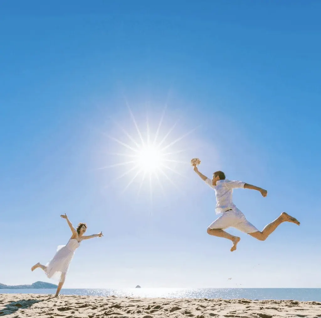 Cute jump shot of a bride and groom under a bright sun