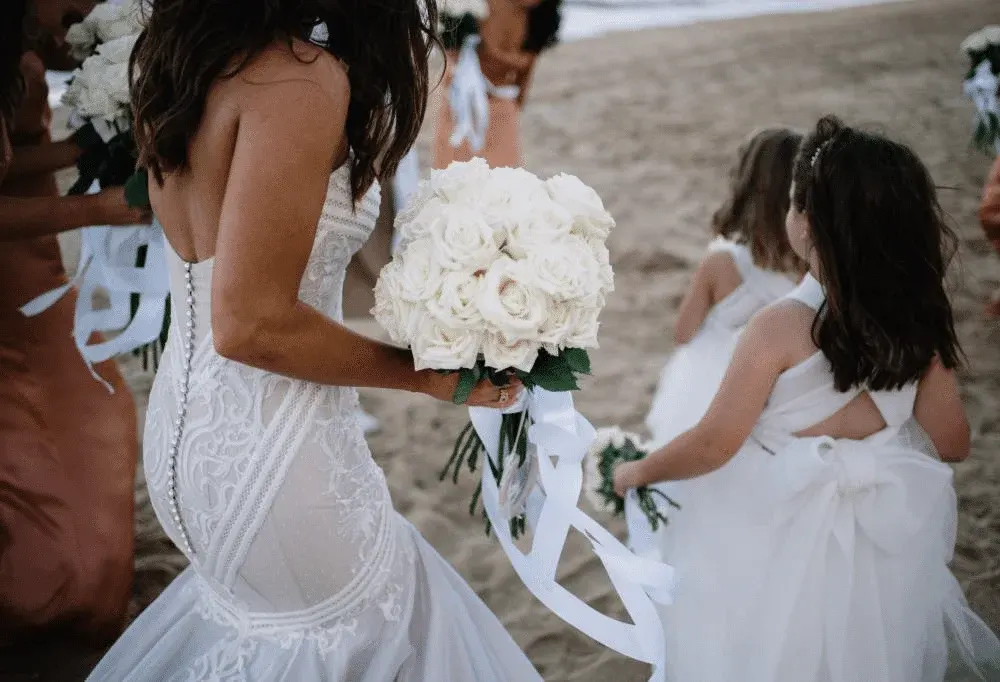 Bride holding a white bouquet surrounded by flower girls