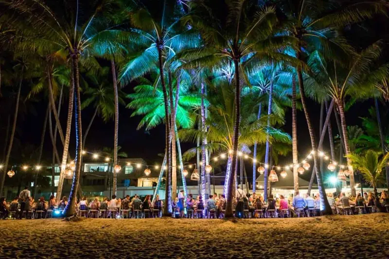 Beachfront reception with several guests enjoying under the palm trees