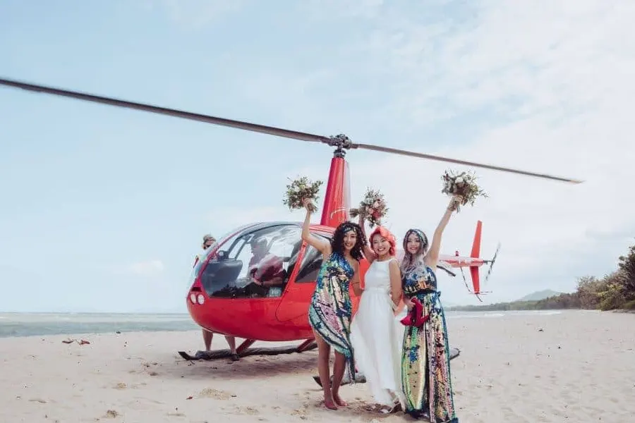 Newlywed bride and friends in front of a red wedding helicopter