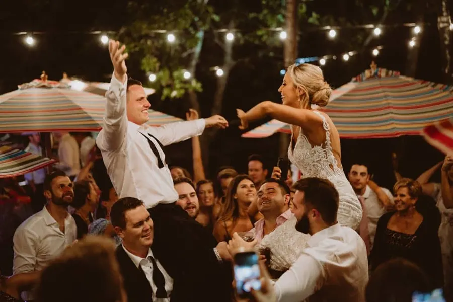Bride and groom being carried by friends on their shoulders as they share a dance