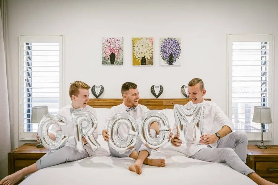 Groom and the groomsmen play around with balloons in the groom’s suite