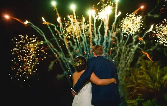 Bride and groom watching fireworks display at night