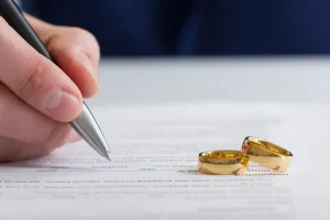 Man signing application for marriage certificate with wedding rings in view