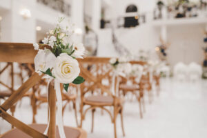 blurred indoor wedding ceremony setup with flower decor on chair in focus