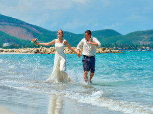 Happy newlyweds running and having fun on the beach