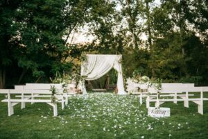 wedding ceremony aisle with white arch in a garden setting