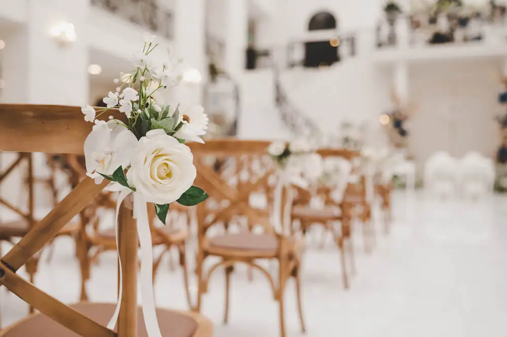 blurred indoor wedding ceremony setup with flower decor on chair in focus